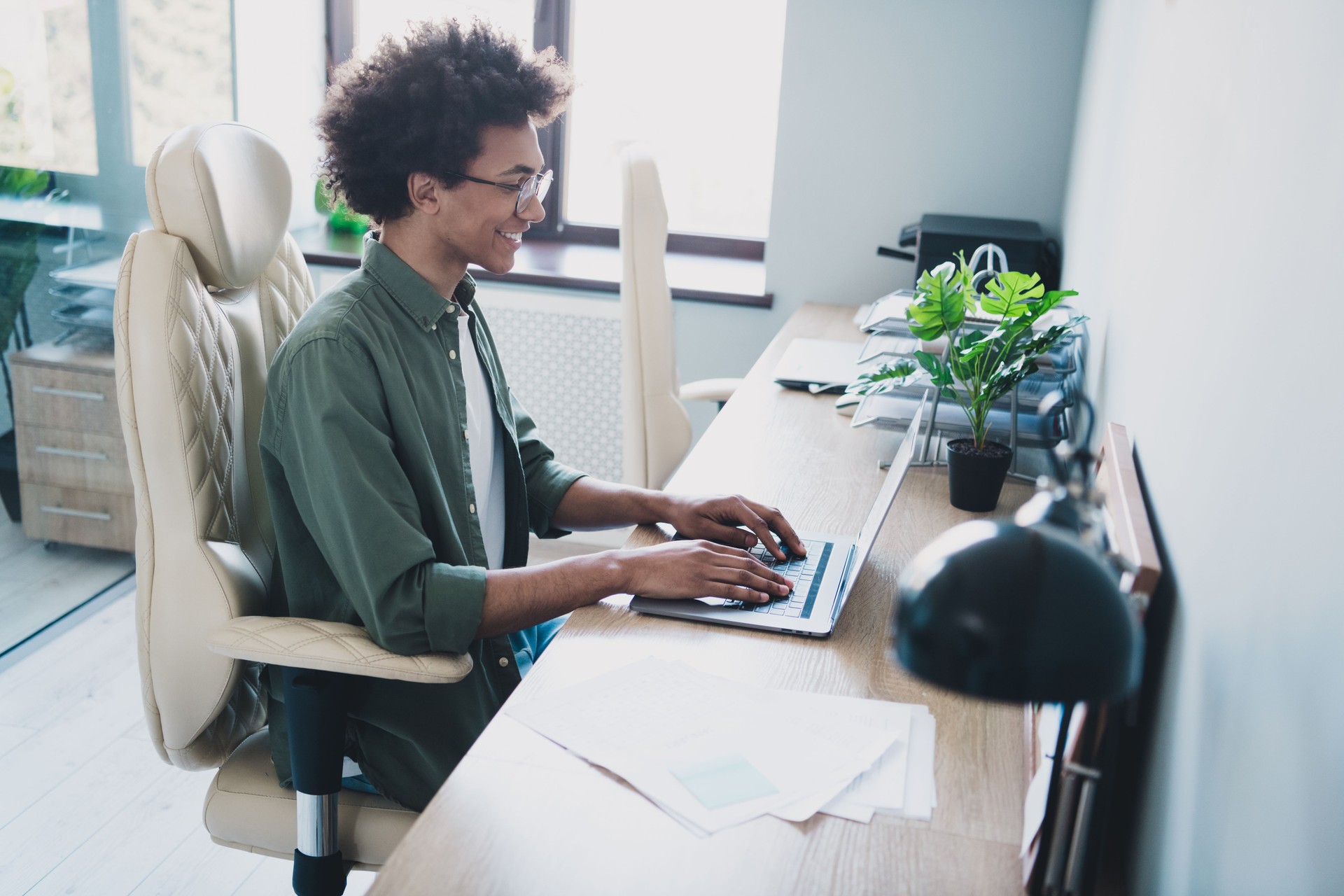 Photo of happy positive broker wear khaki shirt spectacles communicating modern device indoors workshop workstation